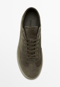 Olijfgroene suède sneaker met een ronde neus, vetersluiting en een gestructureerde afwerking. Zachte binnenzool met een minimalistisch merkembleem.