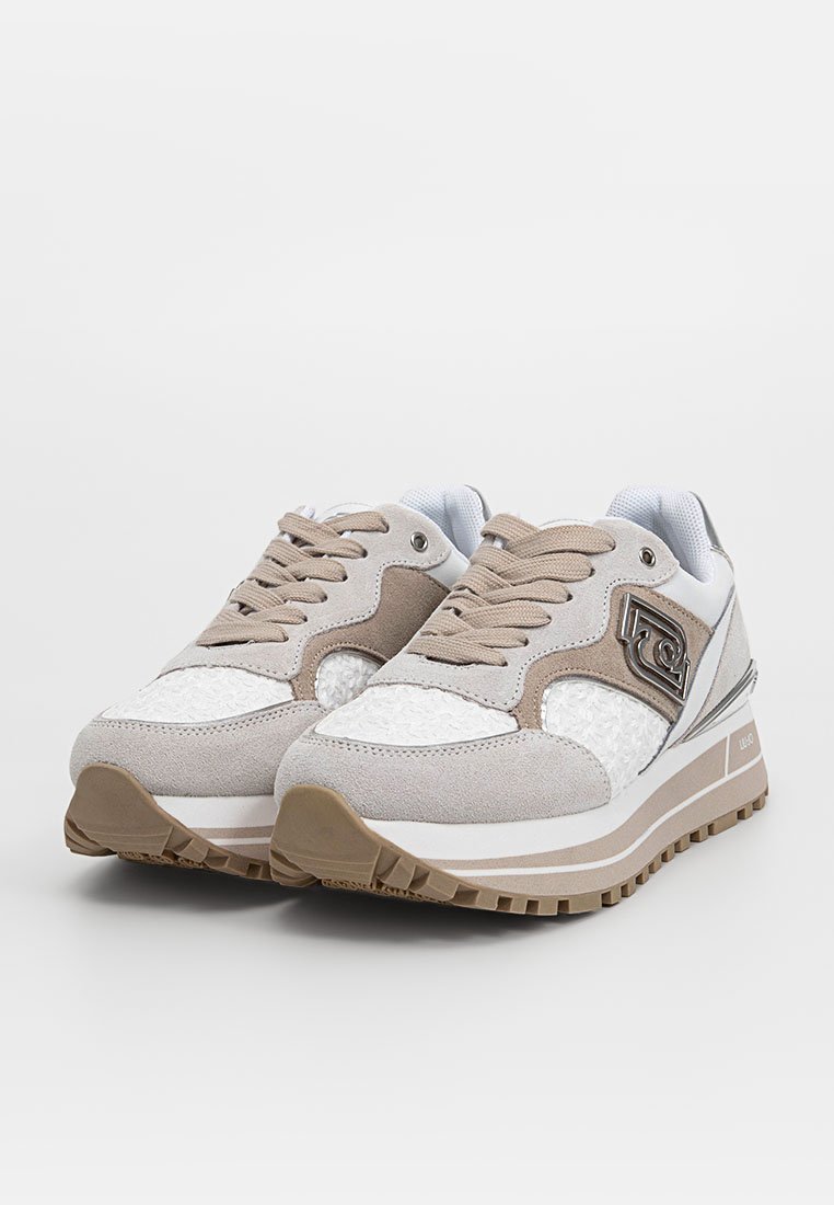 Sneaker beige e bianche con una combinazione di suede e tessuto testurizzato. Presentano un logo, un collare imbottito e una suola in gomma robusta con grip.