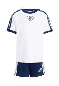 Biele tričko s námorníckym lemovaním a logom srdca; v kombinácii s námorníckymi šortkami s bočnými pruhmi a značkovým detailom. Bavlnený materiál.