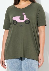 Oliwkowy T-shirt o luźnym kroju i krótkich rękawach, z grafiką różowego skuterka i rokiem "1987" poniżej. Miękka faktura.