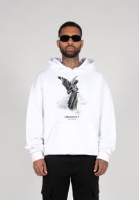 Weißer Hoodie mit einem grafischen Design einer geflügelten Statue auf der Vorderseite. Das Material scheint weich zu sein; beinhaltet eine große Kapuze und eine Vordertasche.