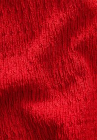 Tessuto rosso texturizzato con un motivo ondulato, che presenta un aspetto sgualcito e una superficie liscia, adatto per varie applicazioni tessili.