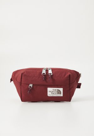 Bordowa nerka z przednimi i górnymi kieszeniami na zamek, na przedzie w centrum naszywka z logo „The North Face Fine Alpine Equipment”.