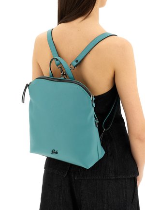 Zaino in pelle turchese con texture liscia, parte superiore curva e cerniere. Presenta spallacci regolabili e un logo sul fondo.