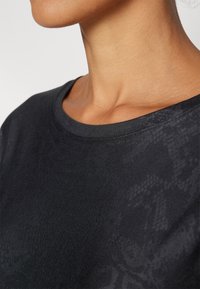 Black short-sleeve shirt featuring a smooth cotton material, round neckline, and subtle textured pattern.