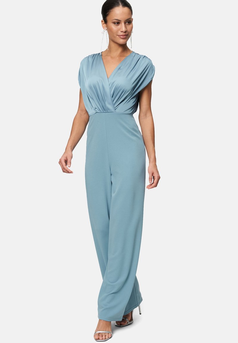 Hellblauer Jumpsuit mit tiefem V-Ausschnitt, gefalteten kurzen Ärmeln und weiter Beinform. Gefertigt aus glattem Stoff mit matter Oberfläche.