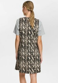 Mouwloze jurk met een grijze T-shirt bovenkant en een rug met een zwart en bruin slangpatroon. Korte lengte, relaxte snit.