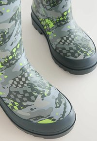 Green and gray patterned rubber rain boots with a textured surface, featuring a durable sole and curved shaft for a snug fit.