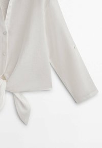 Witte linnen cropped shirt met een strik aan de voorkant, lange mouwen en knoopdetails. Zachte textuur en lichtgewicht ontwerp.