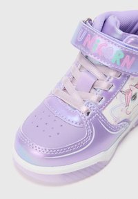 Tênis de cano alto roxo feito de material sintético brilhante. Apresenta um design de unicórnio, atacadores e uma fita rotulada "UNiCoRN". Inclui detalhes texturizados.