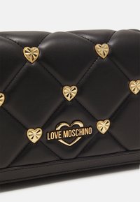 Svart kviltad fusk-lädersväska med gyllene hjärtprydnader och "LOVE MOSCHINO"-logotyp. Konstruerad med en slät textur och dekorativa detaljer.