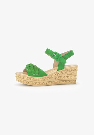 Green suede wedge sandal with a knotted detail on the front, adjustable ankle strap, and textured beige platform.