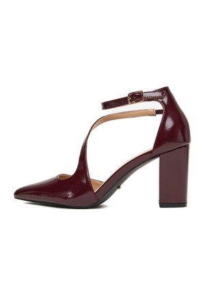 Lakierowany bordowy szpilka z ostrym noskiem, szerokim obcasem i paskiem wokół kostki z złotą klamrą.