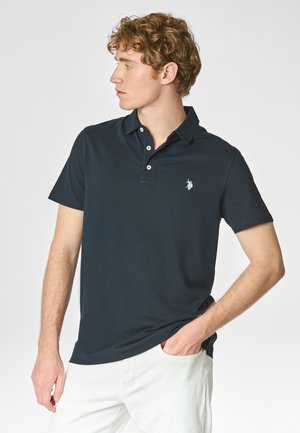 Polo in cotone blu navy, con colletto classico, patta con tre bottoni e un piccolo logo sul lato sinistro del petto. Maniche corte.