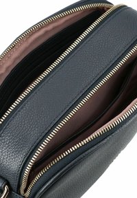 Borsa nera in pelle con due scomparti con cerniera. Dettagli in hardware dorato e una superficie esterna testurizzata. L'interno presenta una morbida fodera marrone a contrasto.