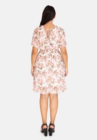 Blommig klänning med rosa bakgrund, korta svepande ärmar och cinchad midja. Har en knytning baktill och en svängig kjol.