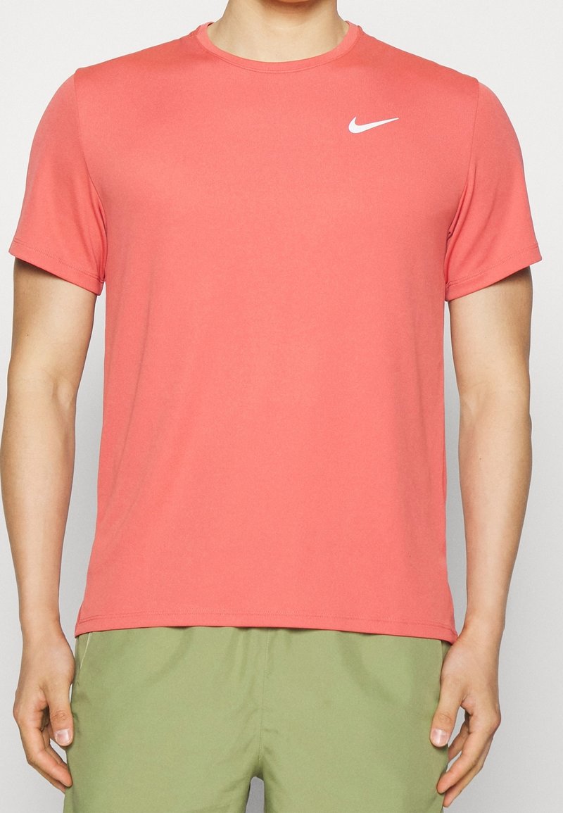 Coral Nike t-shirt in a soft, stretchy fabric. Features short sleeves, a crew neckline, and a white Nike logo on the chest.
