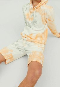 Zestaw hoodie i szortów w stylu tie-dye w jasnych odcieniach zieleni i pomarańczu. Miękka tkanina z regulowanymi sznurkami, z logo z przodu.
