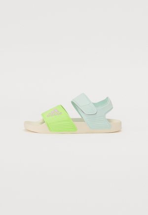 Sandalias verdes y azules claras con correas ajustables, material de goma, acentos texturizados y una suela beige. Presenta el logo en la correa.