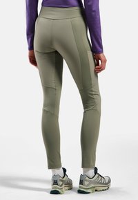 Leggings attillati a vita alta di colore verde oliva chiaro, con cuciture piatte e tasche laterali. Il tessuto appare liscio ed elastico.