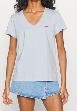 Jasnoniebieski bawełniany t-shirt z dekoltem w serek i krótkimi rękawami, z małym czerwonym logo Levi's na lewej piersi. W połączeniu z dżinsową spódnicą.