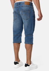 Pantaloni scurți din denim, cu o nuanță albastră estompată, până la genunchi, având un eticheta pe brâu, cinci buzunare și o croială dreaptă cu margini rulate.