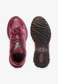 Par de zapatillas deportivas en tonos granate y rosa, vistas desde arriba y desde la suela, con tela de malla y suelas gruesas de goma con suelas texturizadas.