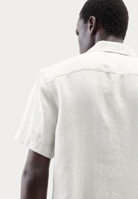 Letvægts kortærmet skjorte i off-white linned. Har en klassisk krave og minimal syning med en tekstureret overflade.