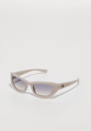 Lunettes de soleil rose clair avec une finition mate, verres rectangulaires dégradés en gris, et un petit logo en métal sur le côté. Design élégant et texture lisse.