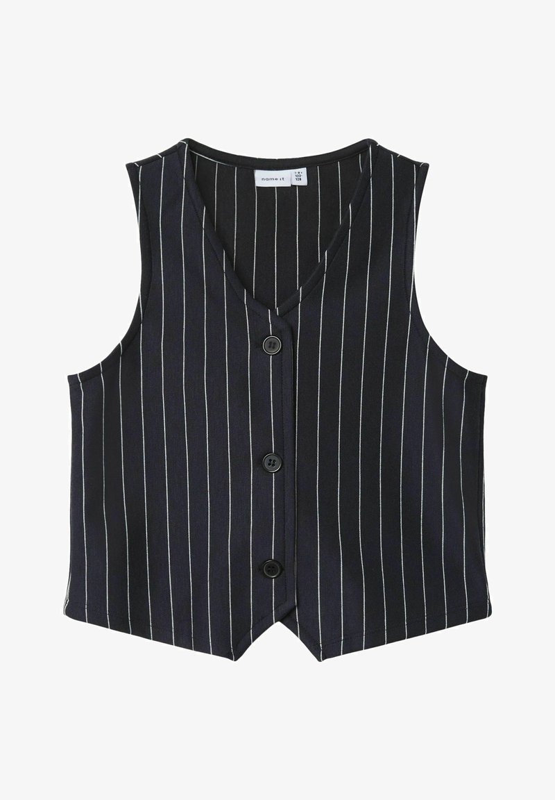 Musta liivi, jossa on valkoiset pystyraidat, v-pääntie, etuvetoketjusuljenta ja hihattomuus. Valmistettu sileästä kankaasta ja rakenteellisesti muotoillusta.