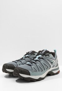 Baskets de sport grises et noires avec tige en mesh, semelle en caoutchouc et détails réfléchissants. Caractéristiques d'un design à lacets et d'un intérieur rembourré.