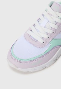 Hvit og pastell lilla sneakers med mintgrønne detaljer, hvite snørebånd, pustende mesh tå, og en tykk hvit såle på en ensfarget bakgrunn.