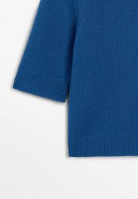 Pull bleu tricoté à manches courtes avec poignets et ourlet côtelés, présenté de profil sur un fond blanc.