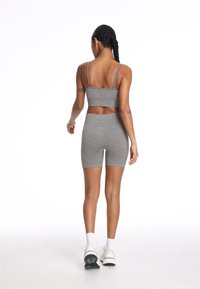 Szary zestaw sportowy z biustonoszem i szortami w teksturowanym materiale, z cienkimi ramiączkami i wysokim stanem. Zaprojektowany dla wygody i swobody ruchów.