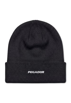 Joven con un gorro negro con el texto "PEGADOR" y una camisa blanca con el mismo logotipo, mirando ligeramente hacia la derecha.