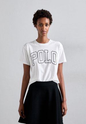Witte katoenen t-shirt met vetgedrukte zwarte "POLO" letters, korte mouwen, ronde hals. Gekoeld met een zwarte rok tot de knie.