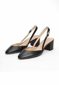 Chaussures slingback en cuir noir avec un bout pointu, un talon carré et un détail de boucle en ton doré sur la bride. Texture lisse et design minimaliste.