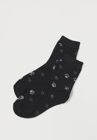 Calcetines de algodón negros con un patrón de huellas de patas grises. Diseñados con un puño acanalado y una textura suave.