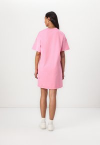 Roze katoenen jurk met korte mouwen, losse pasvorm, knie-lengte, met een ronde halslijn en een zachte textuur. Gemaakt in combinatie met witte sneakers.