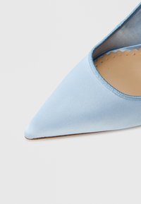 Γαλάζιο σατινέ γυναικείο παπούτσι με ψηλό τακούνι, μυτερή μύτη, λεία υφή και ελαφρώς επενδεδυμένη εσωτερική επιφάνεια. Ένας κομψός και μινιμαλιστικός σχεδιασμός.