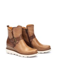 Bottines en cuir marron avec semelle compensée, fermeture éclair sur le côté et accent de boucle décorative. Texture lisse avec des bandes marron contrastantes.