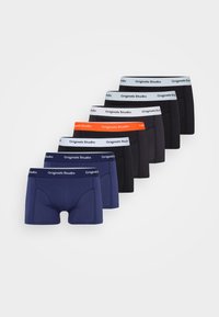 Acht paar boxershorts in verschillende kleuren: marineblauw, zwart en grijs met witte en oranje elastische taillebanden met het label "Originals Studio."