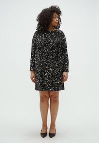 Fekete flitteres ruha hosszú ujjakkal, kerek nyakkivágással és laza szabással. Az anyag sima, csillogóan visszatükröző díszítésekkel.