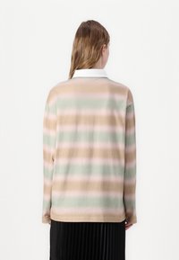 Camisa de mangas longas com gola, apresentando riscas horizontais em verde pastel, rosa e bege. Tecido suave e corte descontraído.