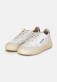 Baskets en cuir blanc avec des accents en suédine beige, embout perforé, lacets plats beige et semelle en caoutchouc. Présente un patch logo sur le côté.