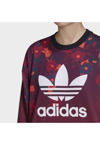 Felpa bordeaux con motivo floreale in rosso e blu navy, dotata di un grande logo Adidas bianco e un colletto a girocollo verticale nero.