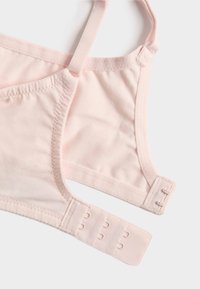 Weiche rosa BH-Träger und Haken-Ösen-Verschluss liegen flach auf weißem Hintergrund.
