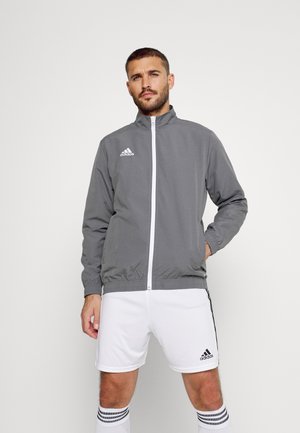 Grijze sportieve jas met een hoge kraag, volledige ritssluiting, elastische manchetten en zoom; met het witte Adidas-logo op de borst.