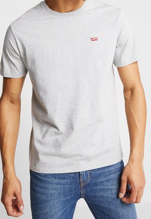 T-shirt en coton gris avec un col rond et des manches courtes, arborant un petit logo rouge Levi's sur la poitrine. Porté avec un jean bleu.