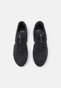 Scarpe da ginnastica nere con tomaia in mesh traspirante, punta rotonda e suola in gomma bianca. Presentano lacci neri e un accento di logo bianco.
